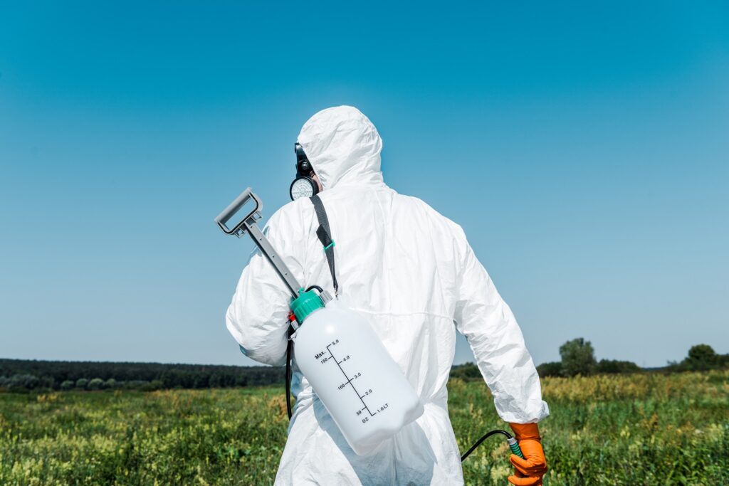 Exterminator in white uniform with toxic spray outside