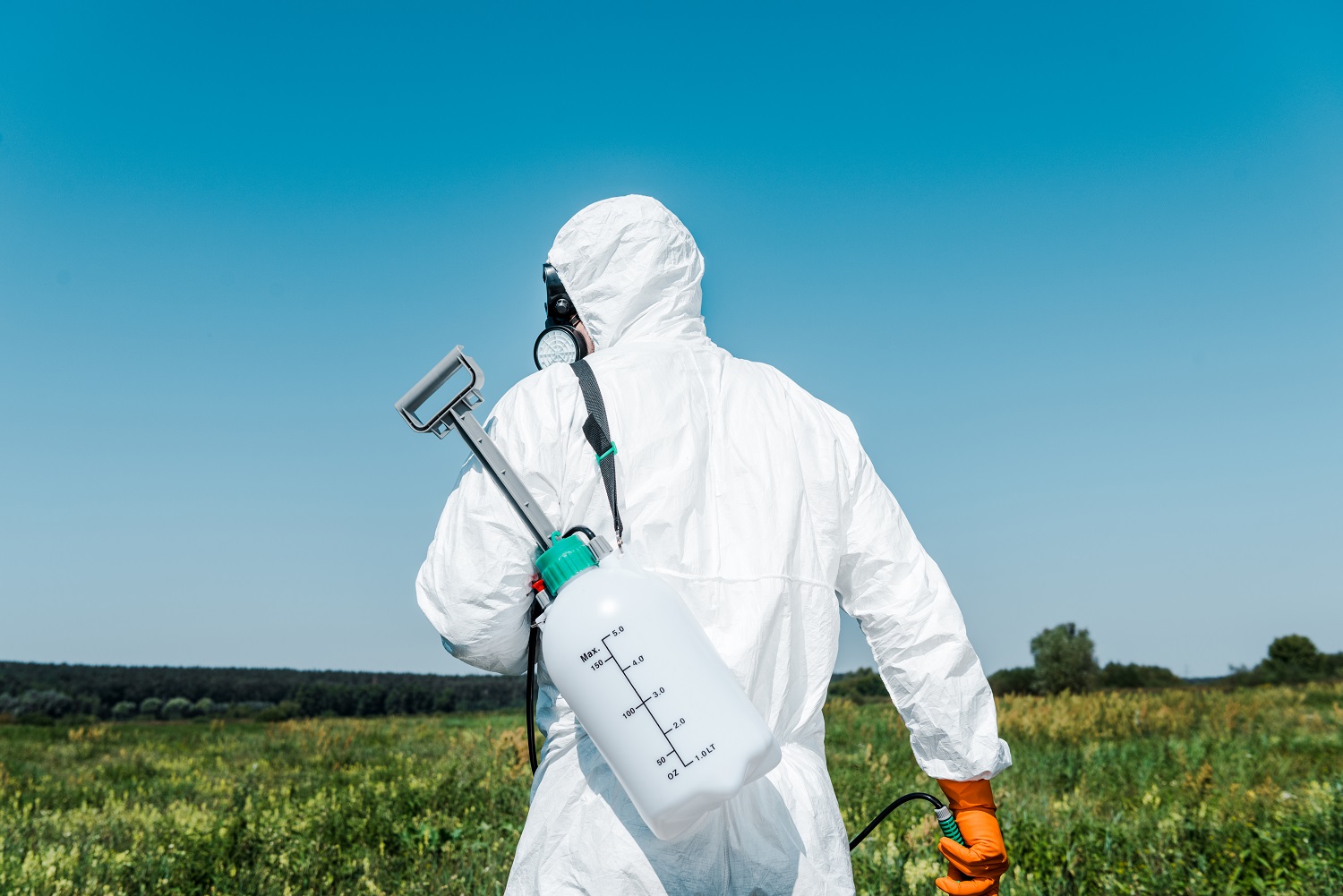 Exterminator in white uniform with toxic spray outside